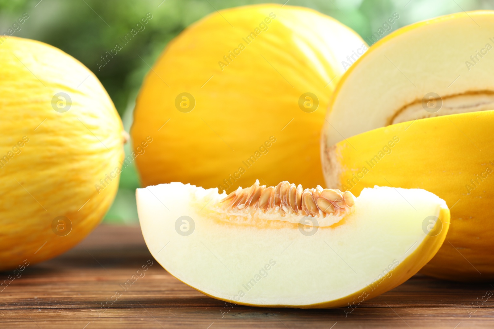 Photo of Fresh ripe melons on wooden table outdoors, closeup