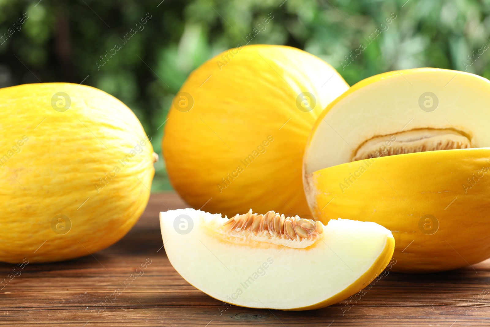 Photo of Fresh ripe melons on wooden table outdoors