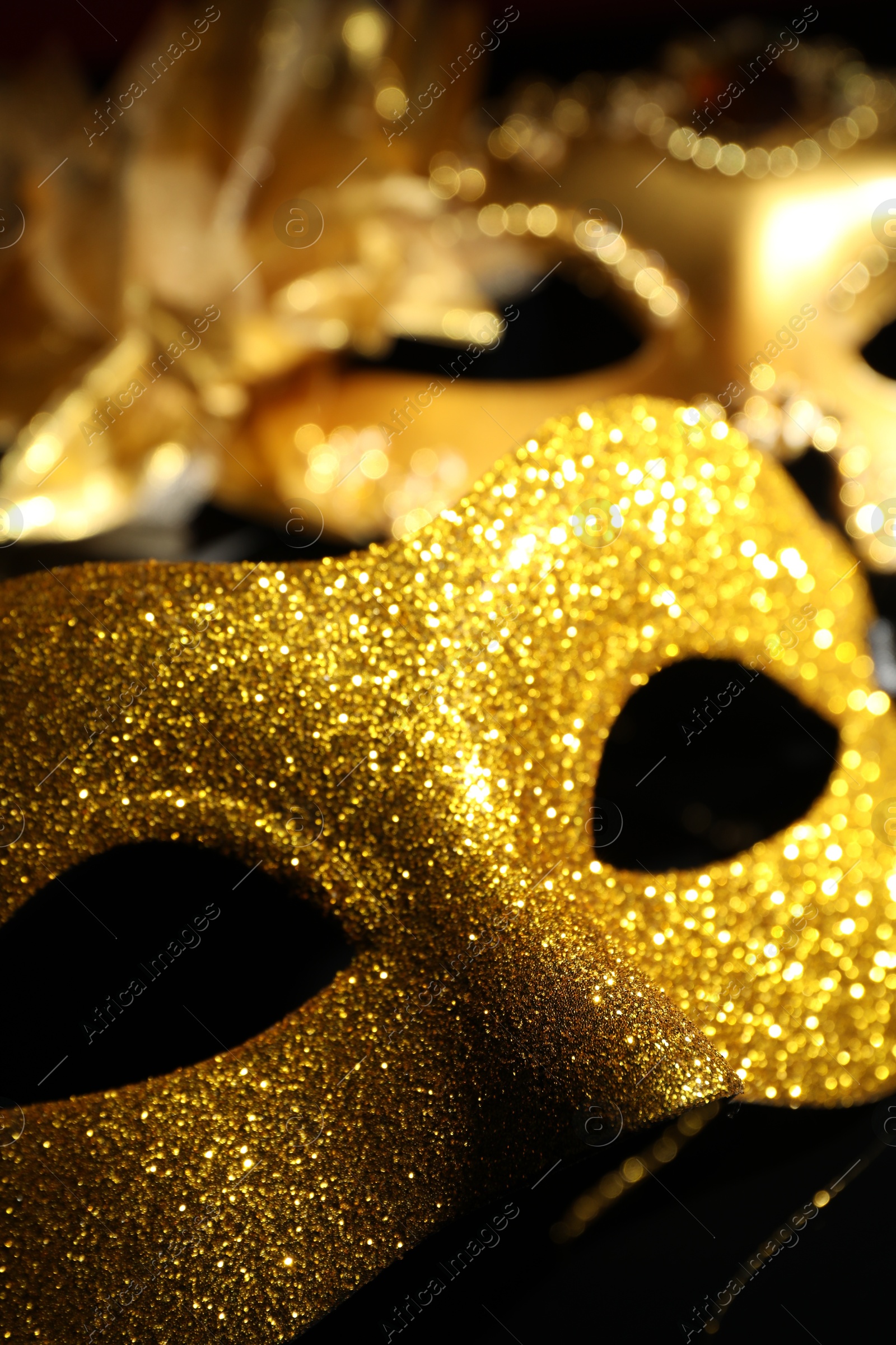 Photo of Beautiful golden carnival masks on black background, closeup