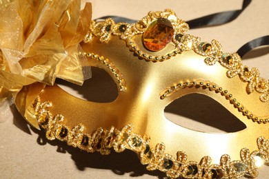 Photo of Beautiful golden carnival mask on beige background, closeup