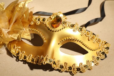 Photo of Beautiful golden carnival mask on beige background