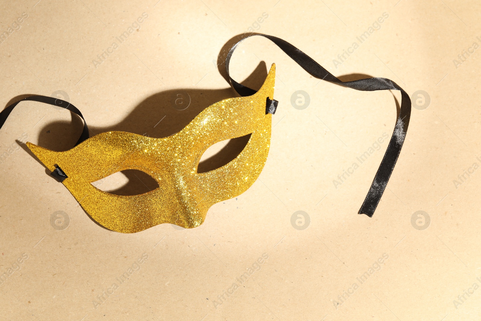 Photo of Beautiful golden carnival mask on beige background, above view