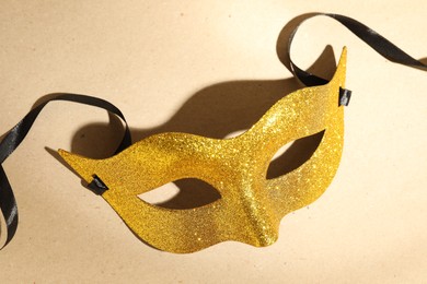 Photo of Beautiful golden carnival mask on beige background, above view