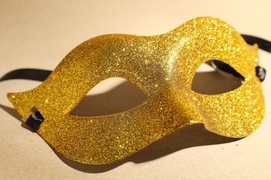 Beautiful golden carnival mask on beige background, closeup