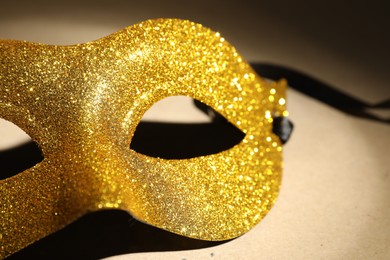 Beautiful golden carnival mask on beige background, closeup