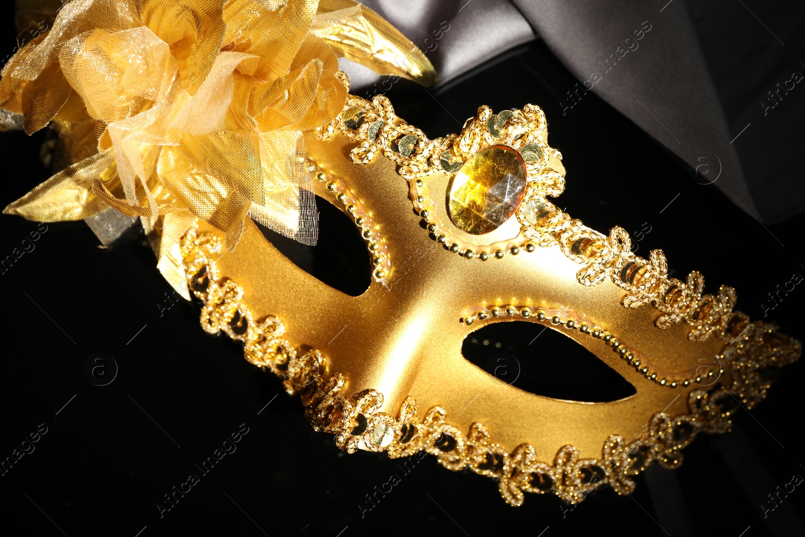 Photo of Beautiful golden carnival mask on black background, above view