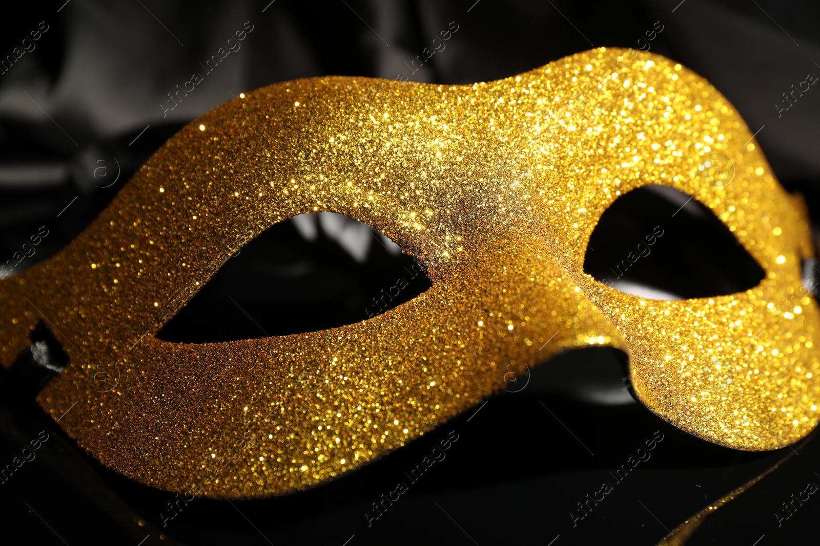 Photo of Beautiful golden carnival mask on black background, closeup