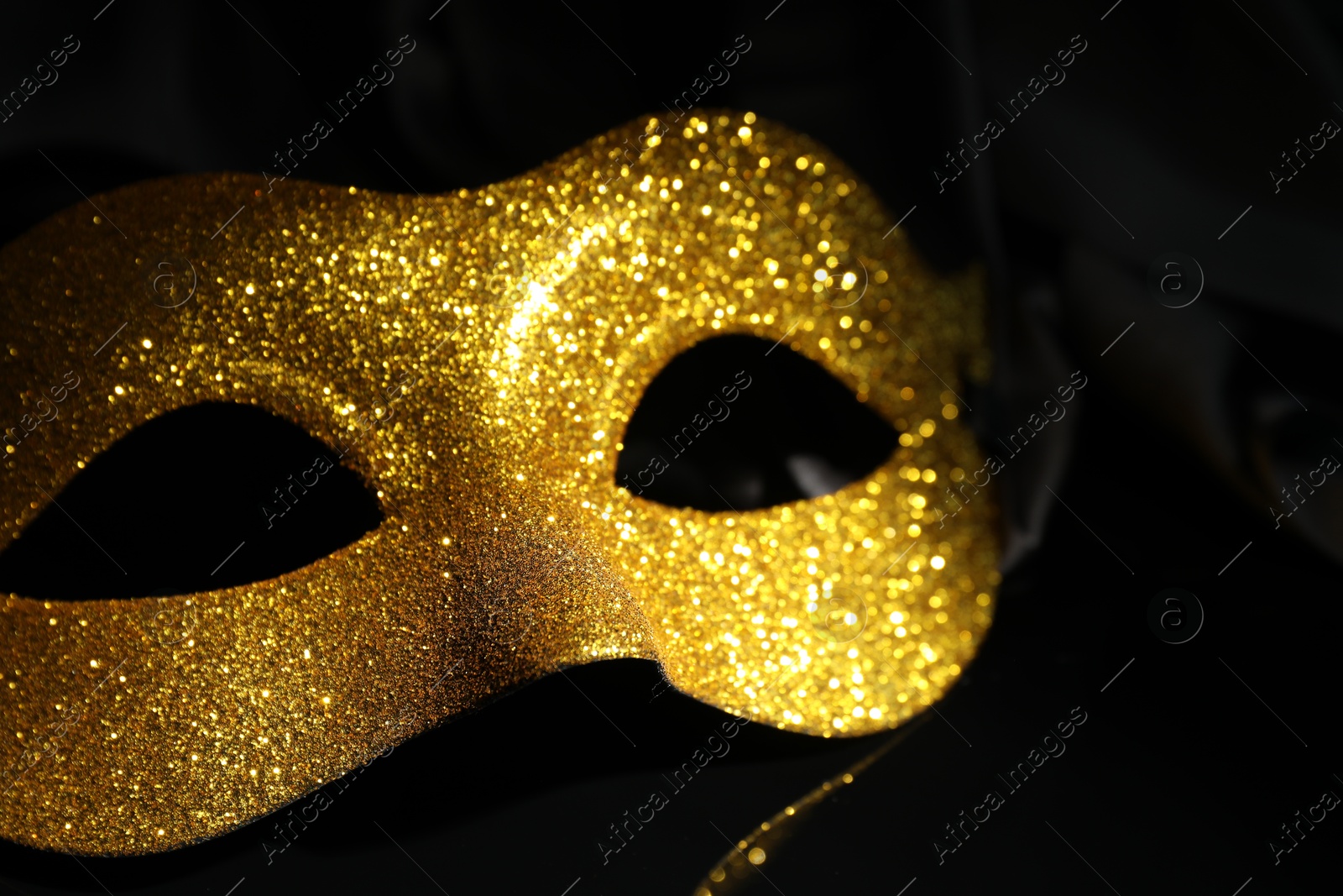 Photo of Beautiful golden carnival mask on black background, closeup