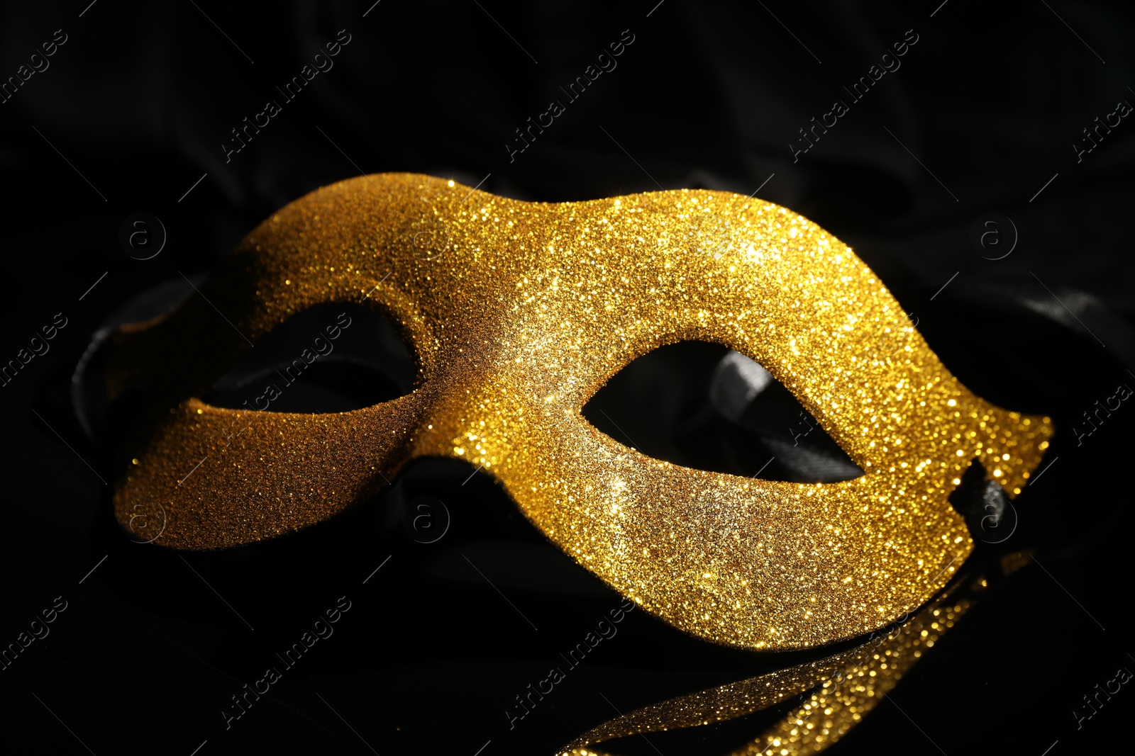 Photo of Beautiful golden carnival mask on black background, closeup