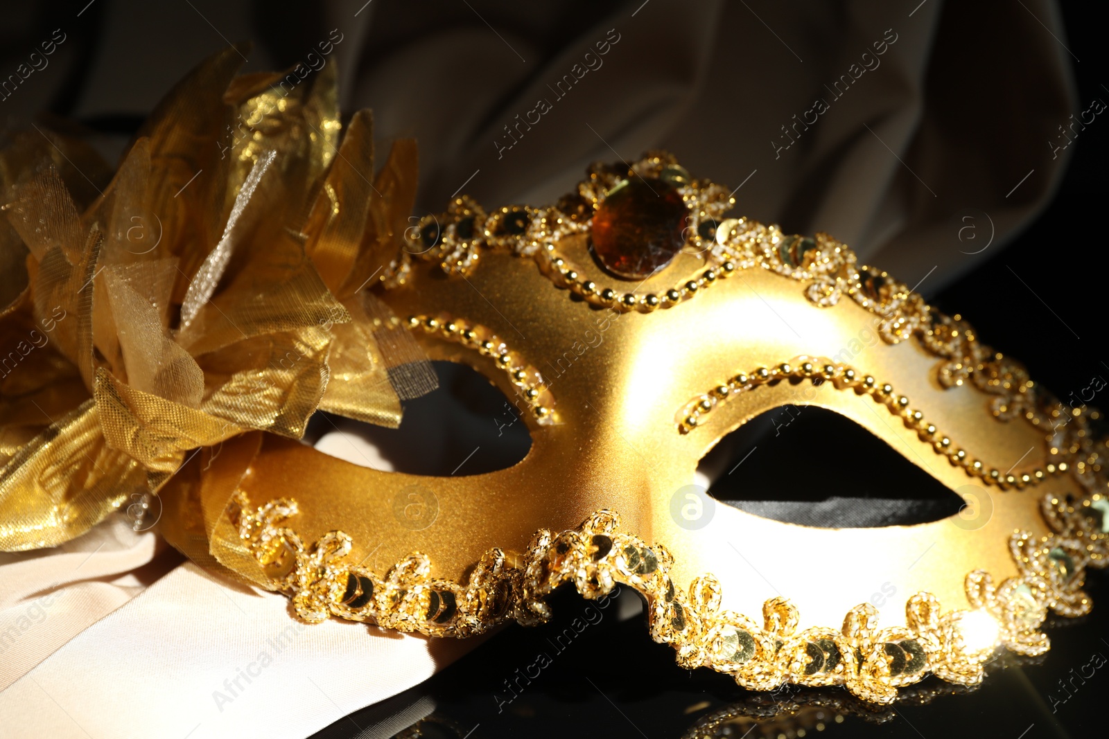 Photo of Beautiful golden carnival mask on black background, closeup