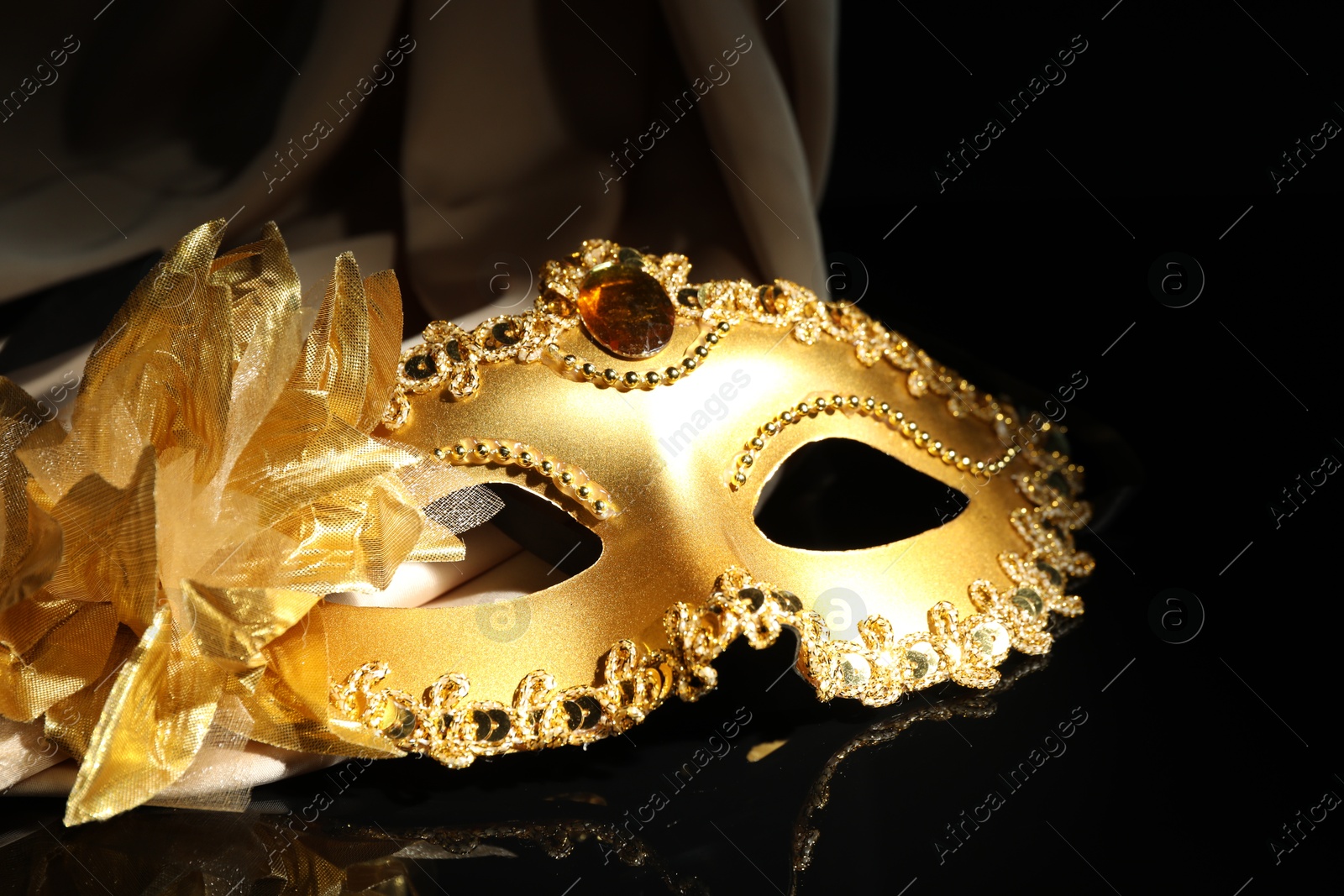 Photo of Beautiful golden carnival mask on black background, closeup