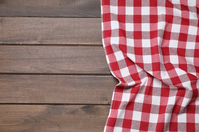 Crumpled tablecloth with checkered pattern on wooden table, top view. Space for text