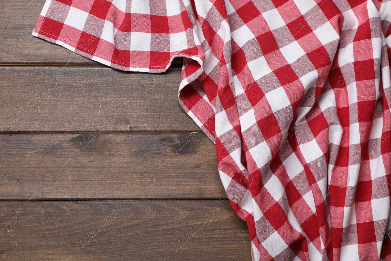 Photo of Crumpled tablecloth with checkered pattern on wooden table, top view. Space for text