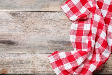 Photo of Crumpled tablecloth with checkered pattern on wooden table, top view. Space for text