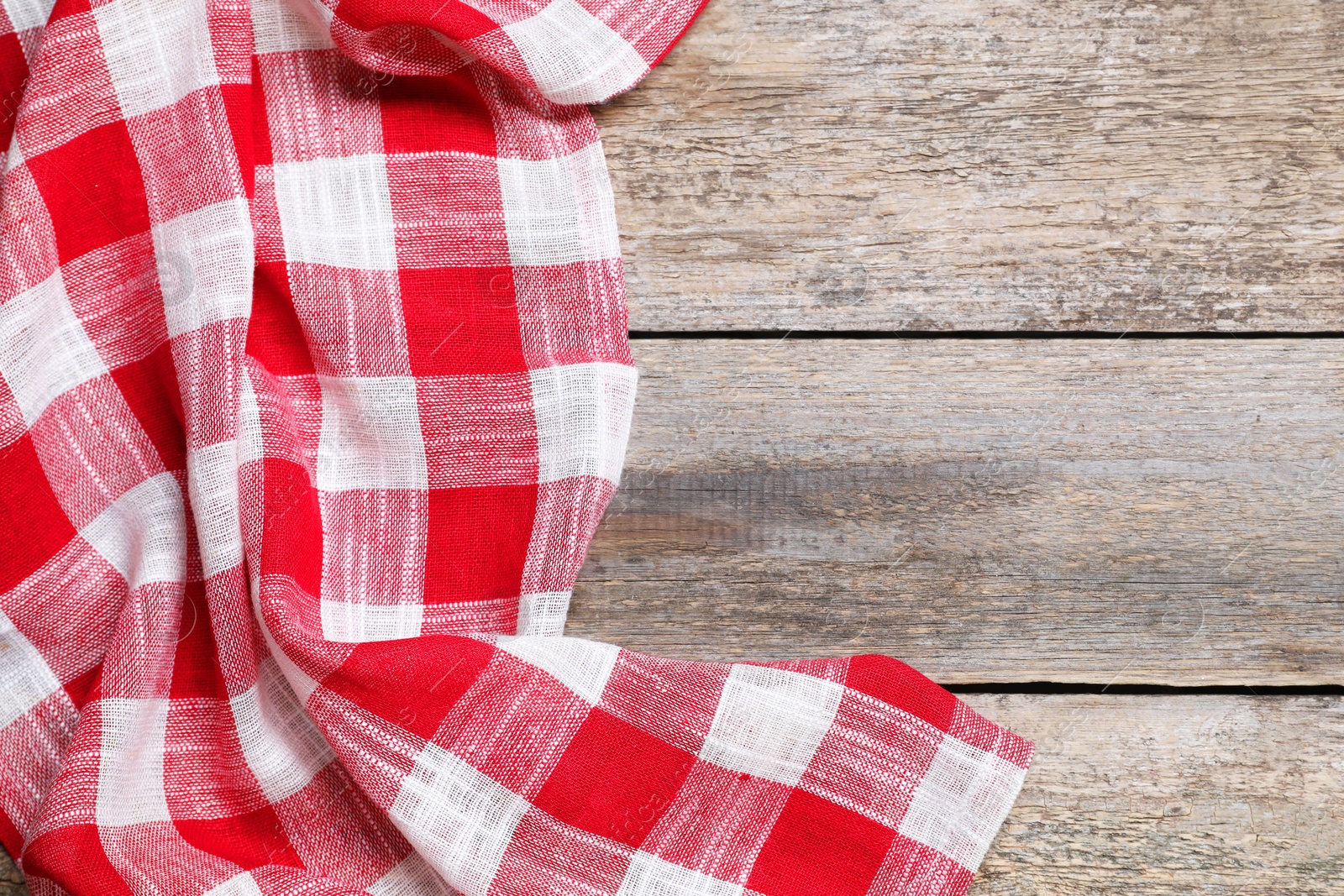 Photo of Crumpled tablecloth with checkered pattern on wooden table, top view. Space for text