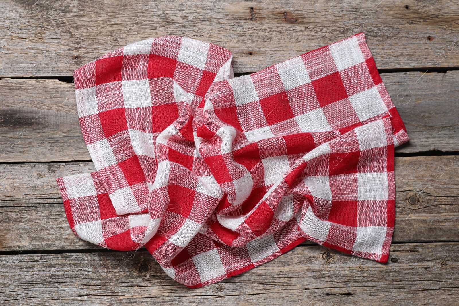 Photo of Crumpled tablecloth with checkered pattern on wooden table, top view