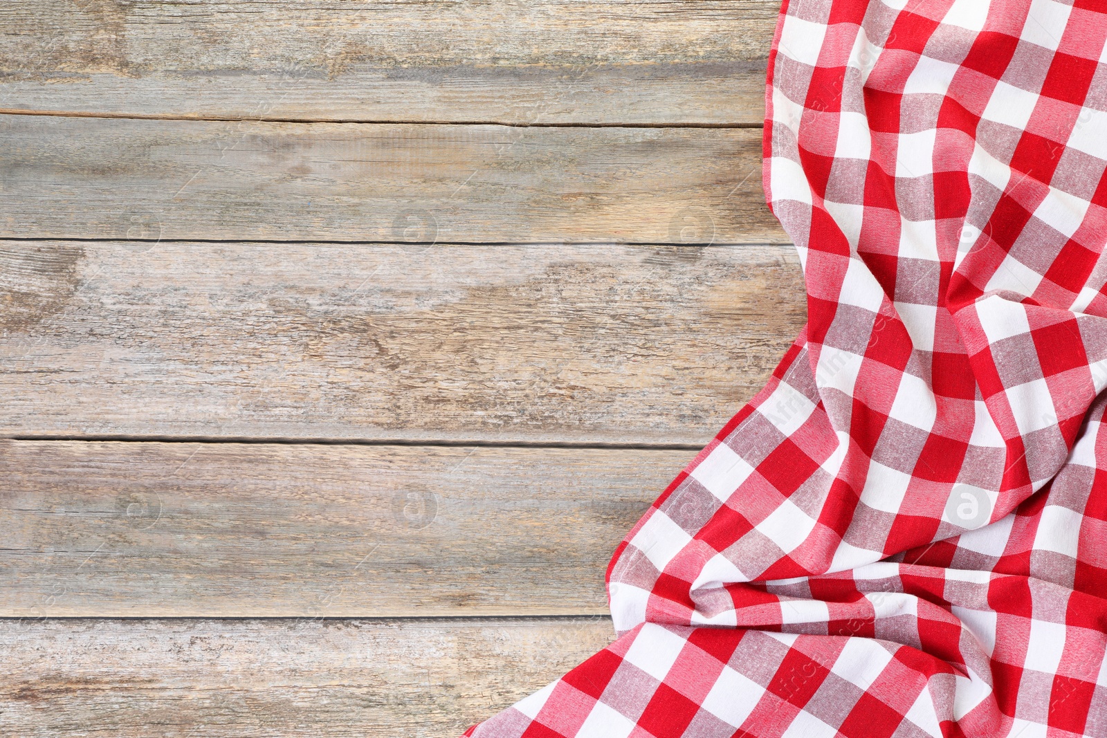 Photo of Crumpled tablecloth with checkered pattern on wooden table, top view. Space for text