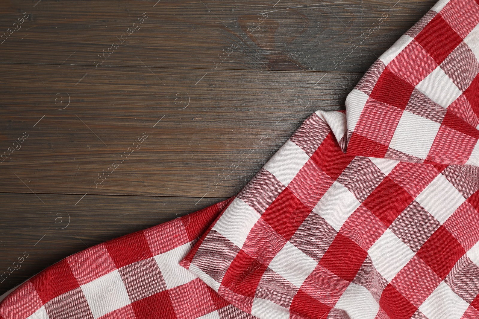 Photo of Crumpled tablecloth with checkered pattern on wooden table, top view. Space for text