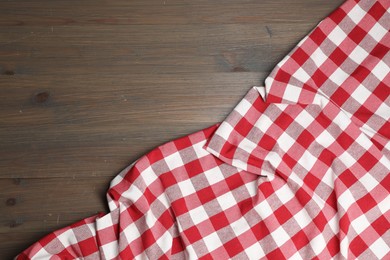 Photo of Crumpled tablecloth with checkered pattern on wooden table, top view. Space for text