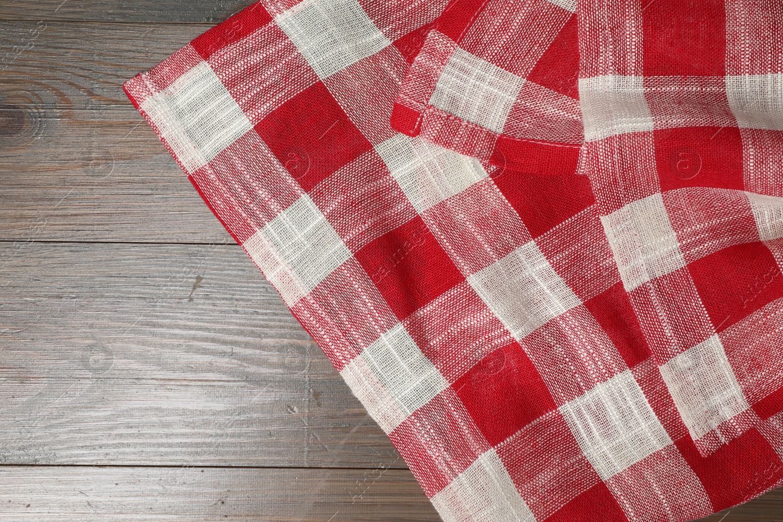 Photo of Crumpled tablecloth with checkered pattern on wooden table, top view