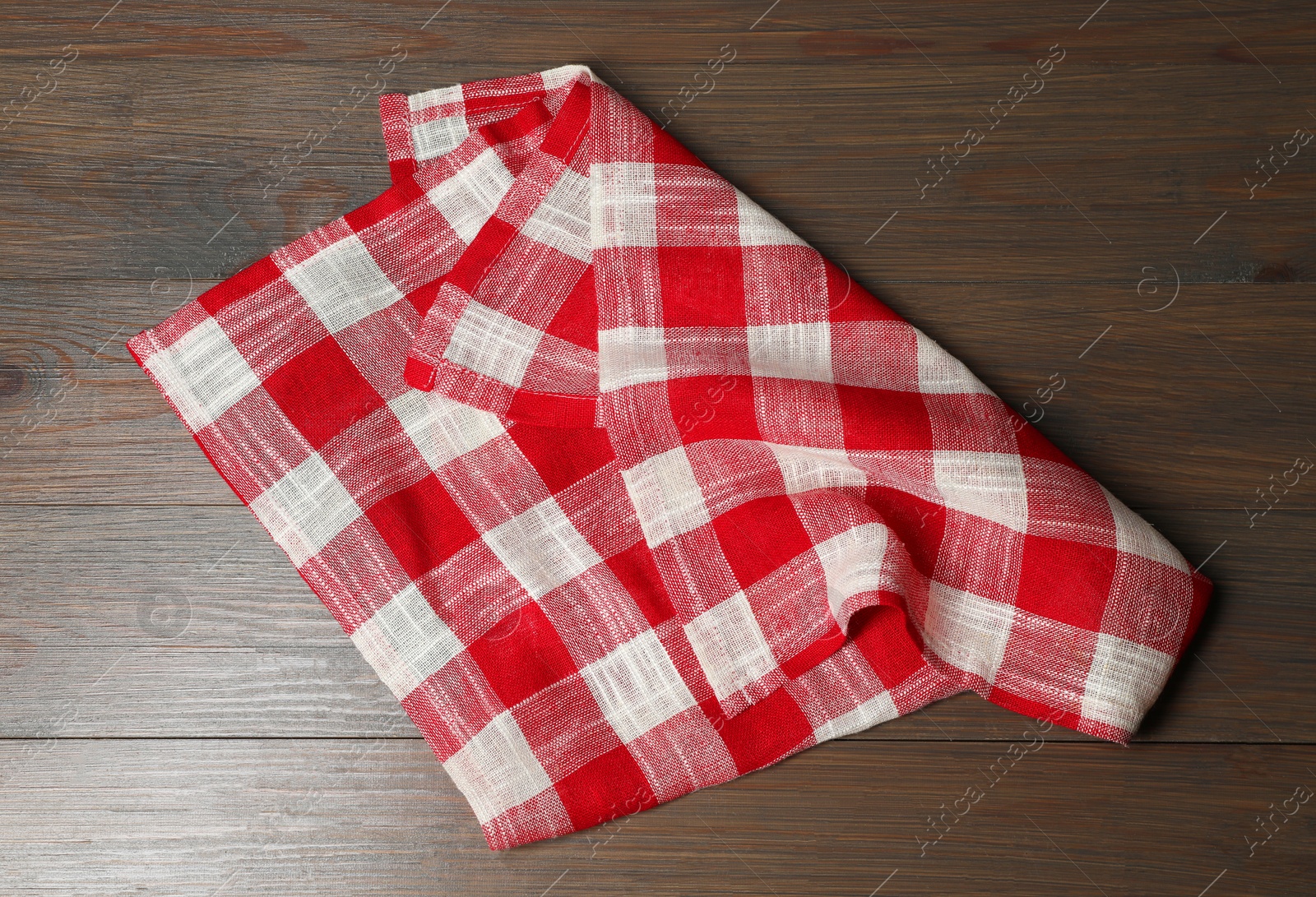 Photo of Crumpled tablecloth with checkered pattern on wooden table, top view