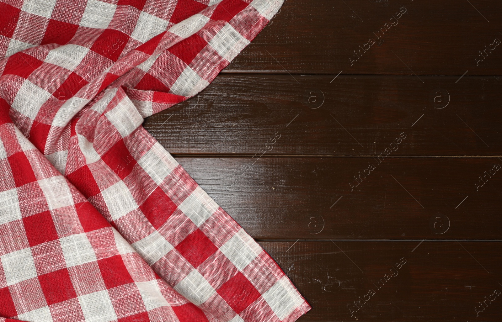 Photo of Crumpled tablecloth with checkered pattern on wooden table, top view. Space for text