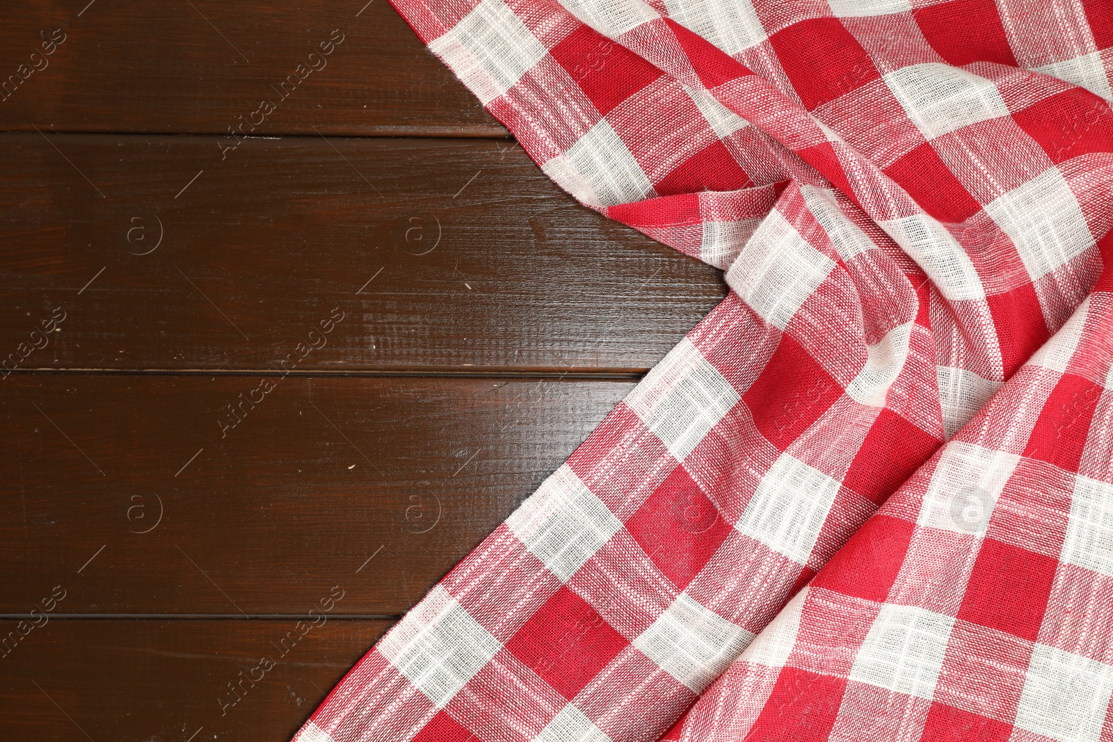 Photo of Crumpled tablecloth with checkered pattern on wooden table, top view. Space for text