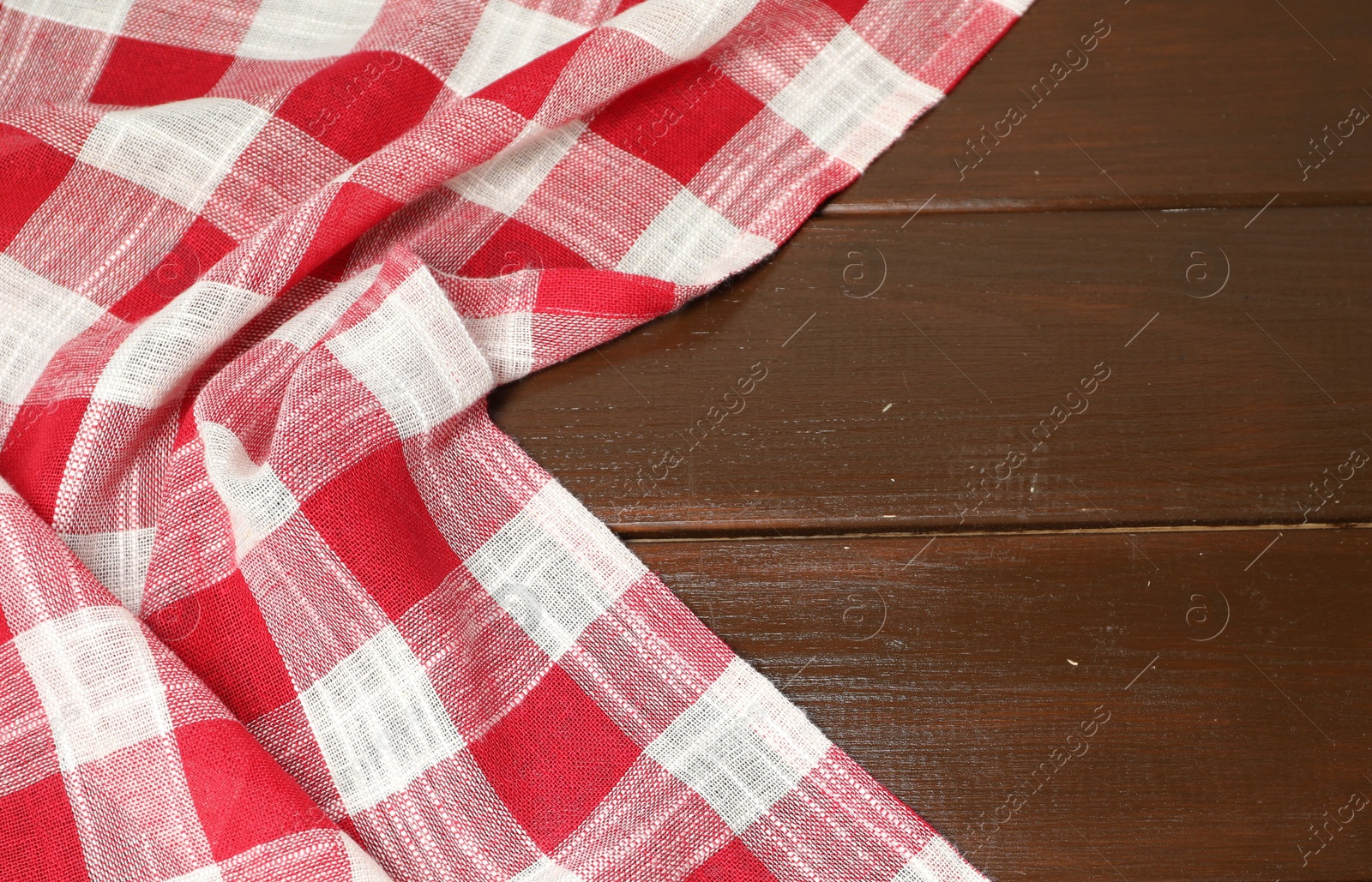 Photo of Crumpled tablecloth with checkered pattern on wooden table, space for text