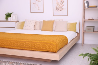 Photo of Large bed near white wall in room. Stylish bedroom interior