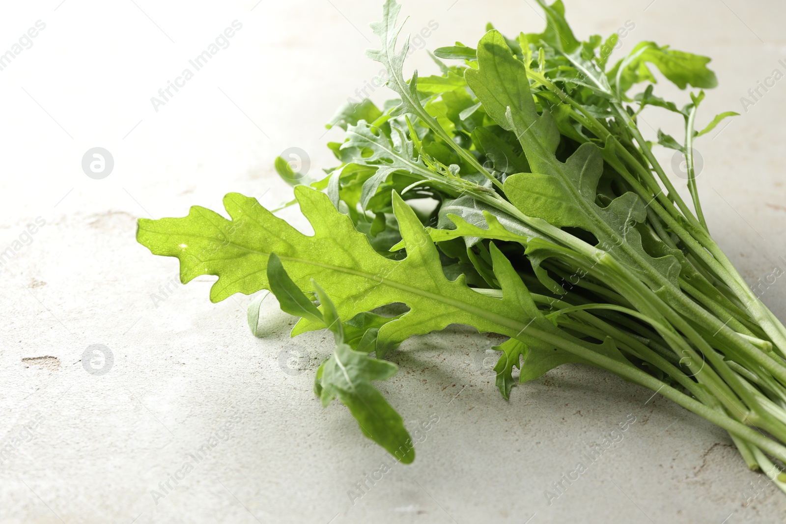 Photo of Many fresh arugula leaves on grey textured table, closeup