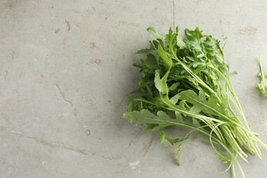 Photo of Many fresh arugula leaves on grey textured table, top view. Space for text