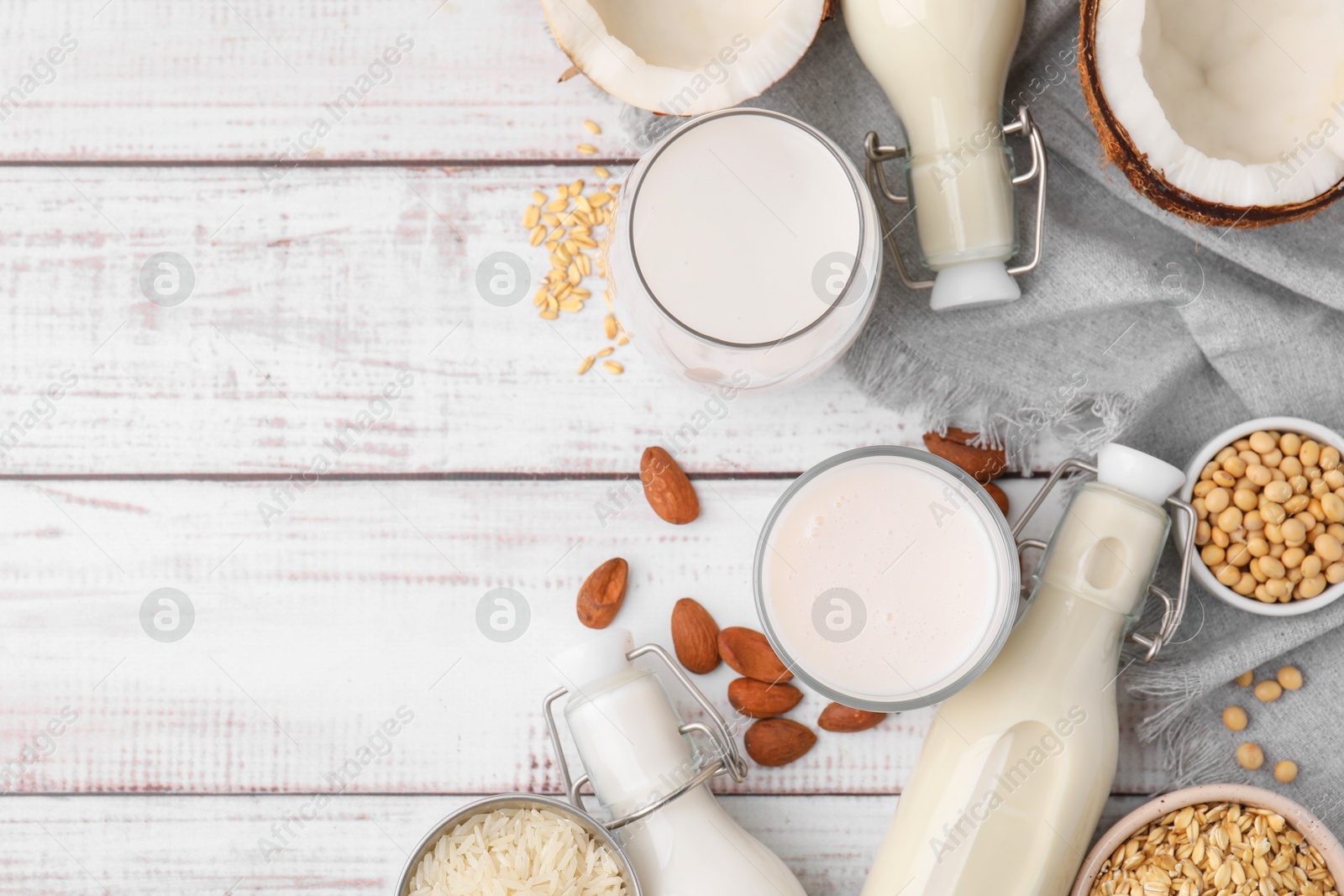 Photo of Different types of vegan milk and ingredients on white wooden table, flat lay. Space for text