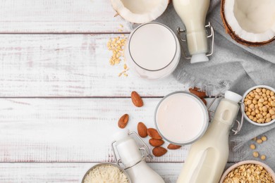 Photo of Different types of vegan milk and ingredients on white wooden table, flat lay. Space for text