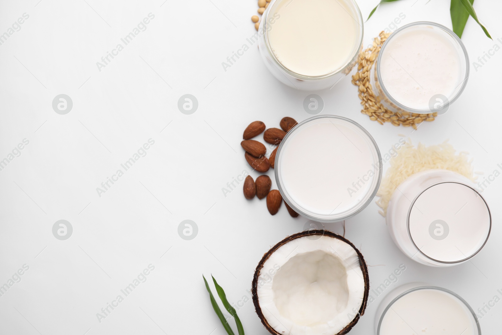 Photo of Different types of vegan milk and ingredients on white table, flat lay. Space for text