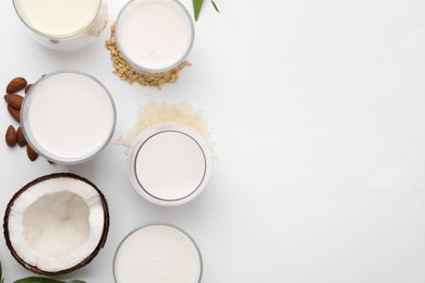 Different types of vegan milk and ingredients on white table, flat lay. Space for text