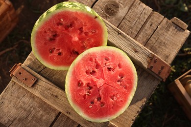 Halves of ripe watermelon on wooden crate outdoors, top view