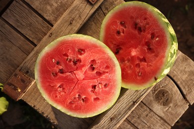 Photo of Halves of ripe watermelon on wooden crate outdoors, top view