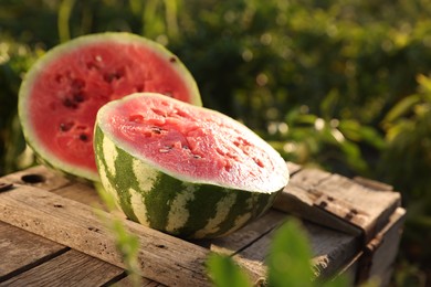 Halves of ripe watermelon on wooden crate outdoors, closeup