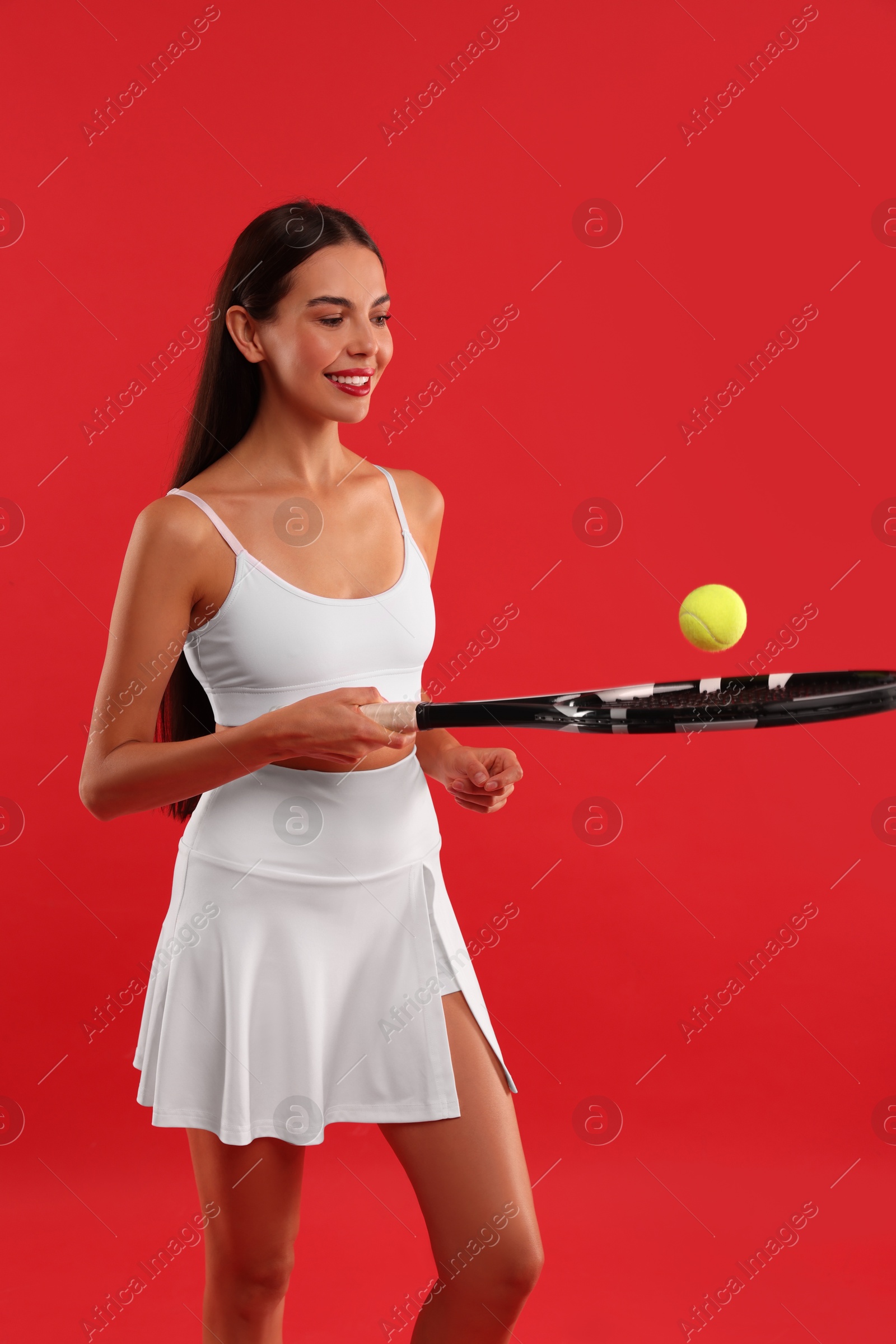 Photo of Happy tennis player with racket and ball on red background