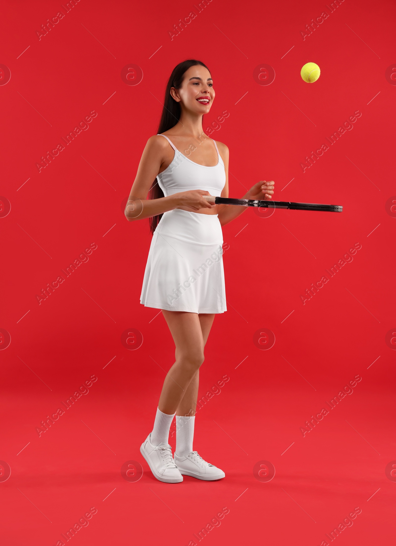 Photo of Happy tennis player with racket and ball on red background