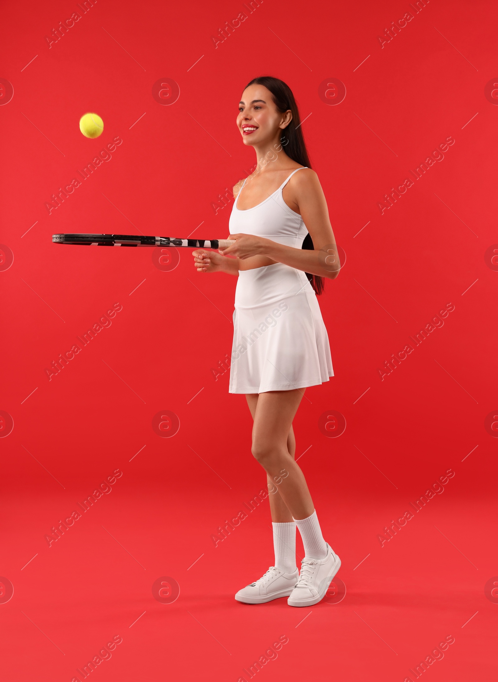 Photo of Happy tennis player with racket and ball on red background