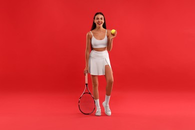 Photo of Beautiful young woman with tennis racket and ball on red background