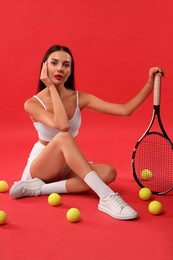 Photo of Beautiful young woman with tennis racket and balls on red background