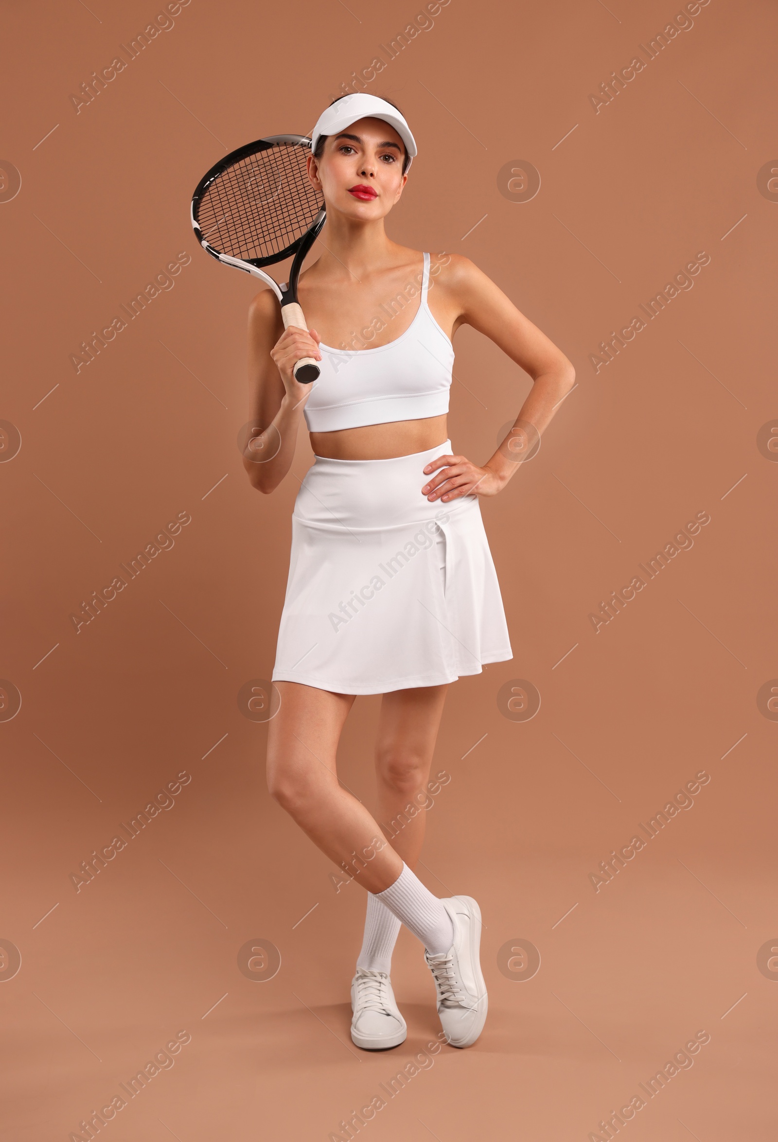 Photo of Beautiful young woman with tennis racket on brown background