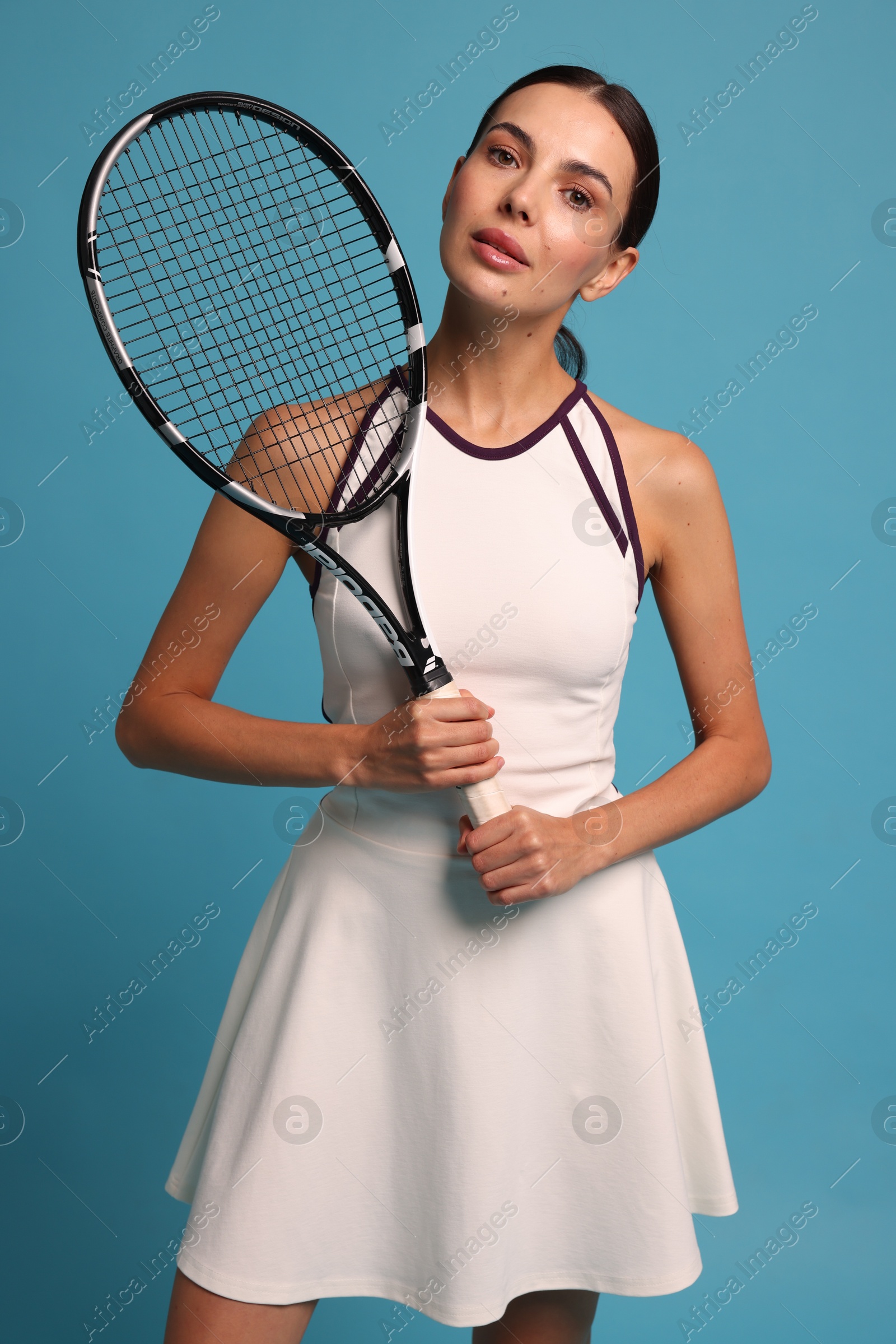 Photo of Beautiful young woman with tennis racket on light blue background