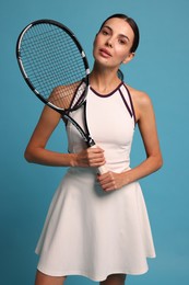 Beautiful young woman with tennis racket on light blue background