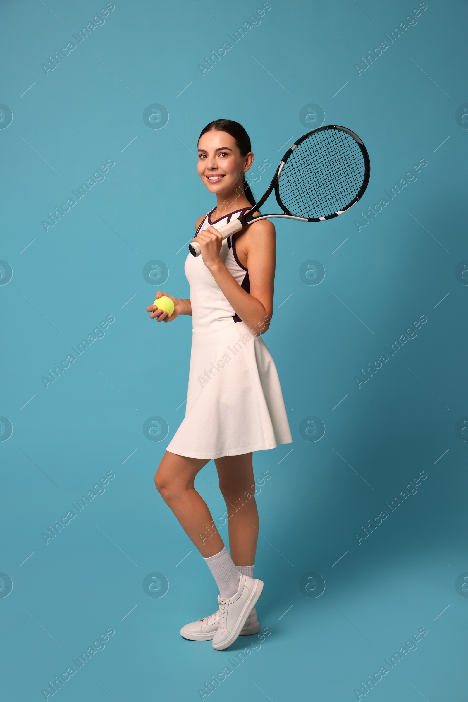 Photo of Happy tennis player with racket and ball on light blue background