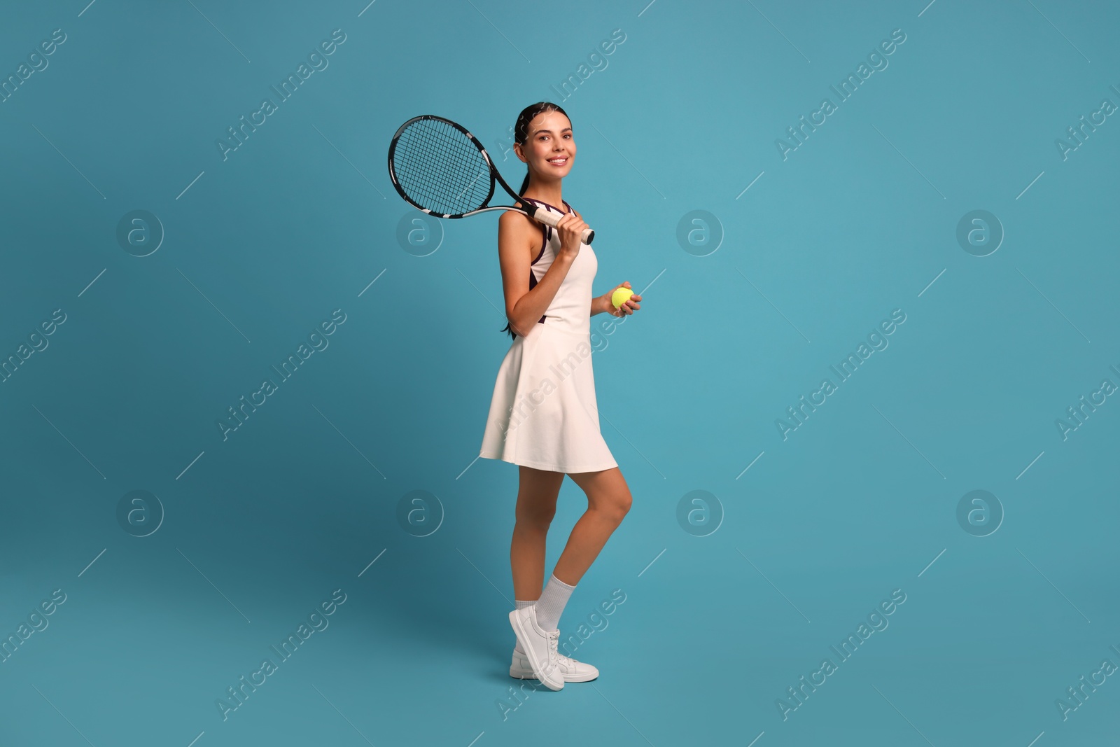 Photo of Happy tennis player with racket and ball on light blue background