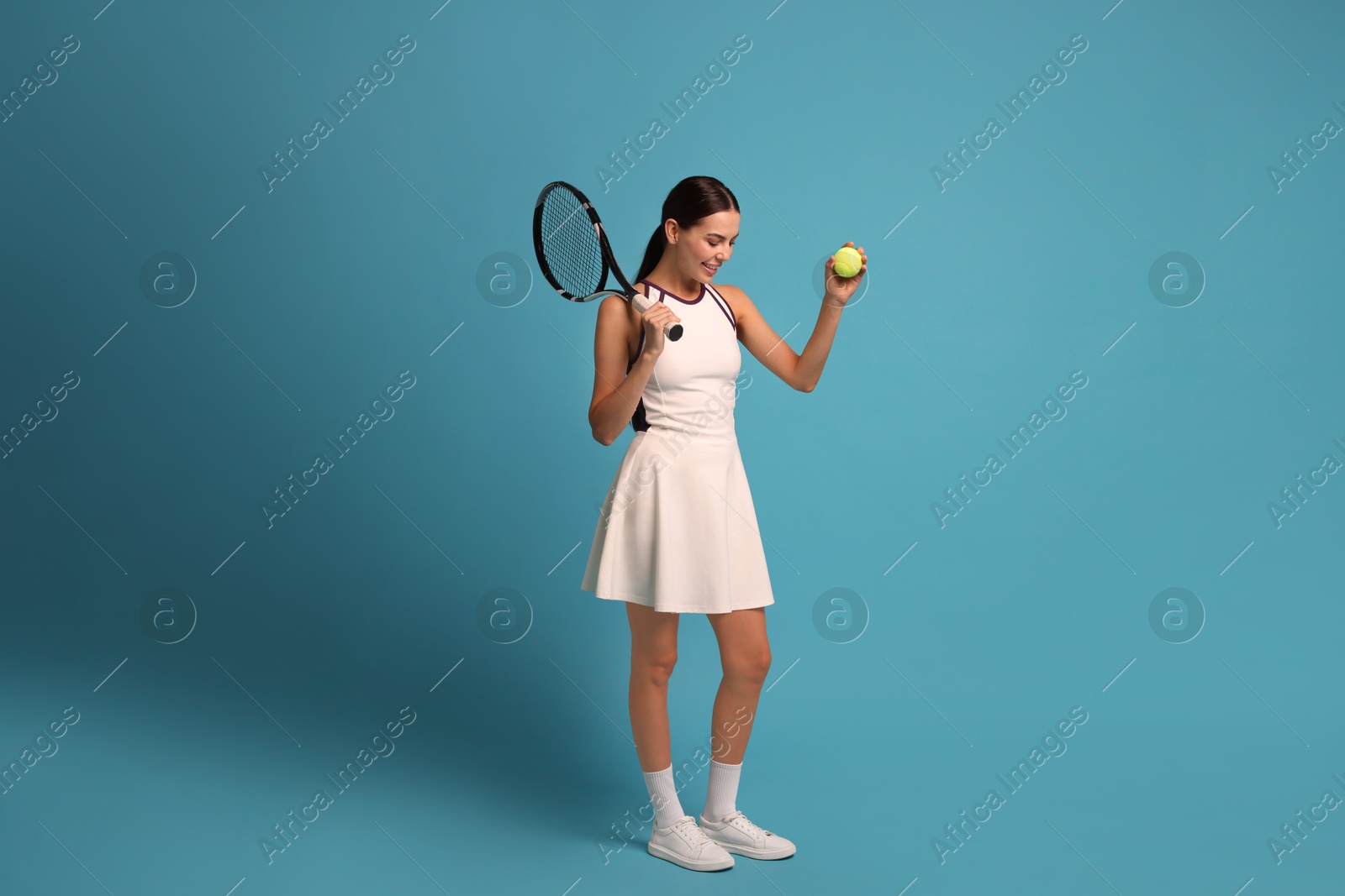 Photo of Happy tennis player with racket and ball on light blue background