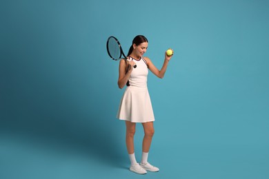 Happy tennis player with racket and ball on light blue background